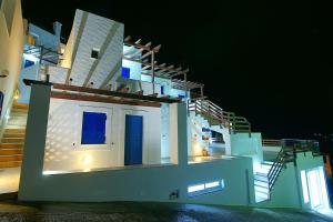 a white building with blue doors and stairs at night at Vasilis Studios in Myrties