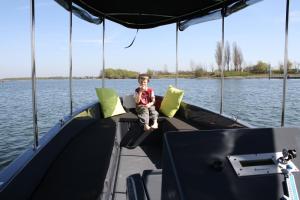 Ein kleiner Junge, der vor einem Boot sitzt. in der Unterkunft Botel Ophoven in Kinrooi