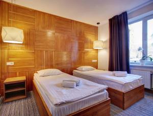 two beds in a room with wooden walls at Valentyna in Lviv