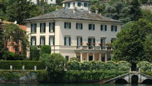 a large white house on the side of a river at VECCHIA LUNA APARTMENT LENNO with Pool by Italian Apartments in Lenno