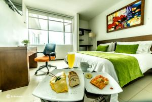 um quarto de hotel com uma cama e uma mesa com comida em Hotel Titanium Plaza em Barrancabermeja