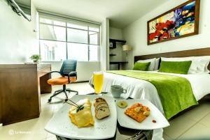 a hotel room with a bed and a table with food on it at Hotel Titanium Plaza in Barrancabermeja