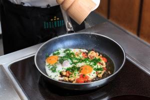 a pan with eggs and vegetables on a stove at Kneipp- und Wellvitalhotel Edelweiss in Bad Wörishofen