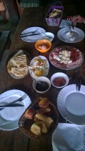 a wooden table topped with plates and bowls of food at Bungalows Ivona in Bastasi