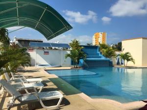 a swimming pool with chaise lounge chairs next to a building at Tonsupa Esmeraldas in Tonsupa