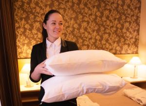 una mujer en una habitación sosteniendo un montón de almohadas en von ROSEN spa, en Mäetaguse
