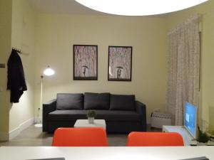 sala de estar con sofá negro y sillas de color naranja en El Católico 56, en Valencia