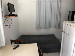 a room with a bed and a table and a television at Pousada Residencial Família Dragone in Bombinhas