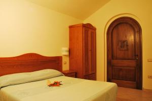 a bedroom with a bed and a wooden cabinet at Hotel Turismo Rurale Villa Maria Caterina in Cala Gonone