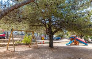 - une aire de jeux avec un arbre et un toboggan dans l'établissement Victoria Mobilehome Jezera Village Holiday Resort, à Jezera