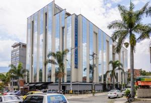 een groot gebouw met palmbomen op een parkeerplaats bij Hotel Sauces del Estadio in Medellín