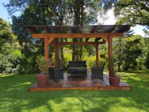 a wooden gazebo with two chairs and a bench at Residencial Pousada do Serrano in Gramado