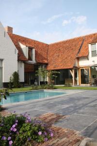 ein Haus mit einem Kacheldach und einem Pool in der Unterkunft de Gasterie in Koksijde