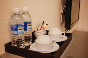 ein Tablett mit zwei Flaschen Wasser und Tassen in der Unterkunft Art Cottage Hotel in Ipoh