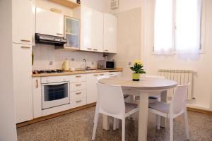 ヴェネツィアにあるVenice Flat S'Elenaのキッチン(テーブル、白いキャビネット、テーブル、椅子付)