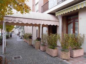 a street with potted plants on a sidewalk next to a building at Hotel La Noce in Chivasso