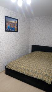 トヴェリにあるАпартаменты на Володарскогоのベッドルーム1室(ベッド1台付)が備わります。壁に絵が飾られています。