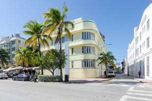 een geel gebouw met palmbomen voor een straat bij Ocean Drive Studio Historic Building minutes walk to the Beach. in Miami Beach