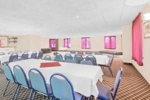 Days Inn by Wyndham Springfield/Phil.Intl Airport في سبرينغفيلد: قاعة المؤتمرات مع الطاولات البيضاء والكراسي الزرقاء
