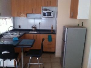 a kitchen with a refrigerator and a table with chairs at MV Homestudio in Viña del Mar
