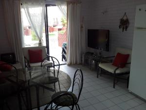 een woonkamer met een tafel en stoelen en een televisie bij Bahia Inglesa Apartamentos in Bahia Inglesa