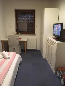 フィラッハにあるSingle Room in Warmbadのベッド、テレビ、デスクが備わる客室です。