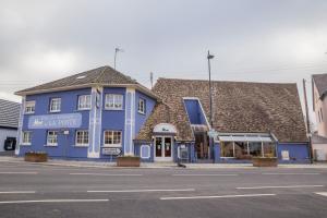 un bâtiment bleu sur le côté d'une rue dans l'établissement Hotel Restaurant De La Poste Mulhouse Ottmarsheim, à Bantzenheim