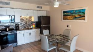 une cuisine avec une table et des chaises et une cuisine avec des placards blancs dans l'établissement Gulf and beach view apartment 403, à Longboat Key