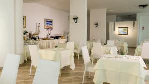 una sala da pranzo con tavoli bianchi e sedie bianche di Hotel Scialara a Vieste