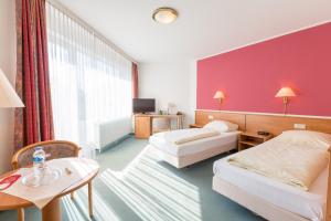 Cette chambre comprend 2 lits et une table. dans l'établissement Aparthotel Berlin, à Bad Nenndorf