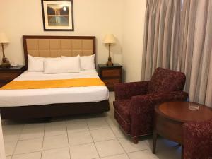 a hotel room with a bed and a chair at Hotel Guillen Jr in Tijuana