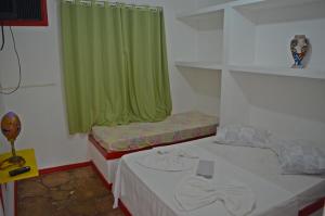 a room with two beds with a green curtain at Pousada Gipsy in Arembepe