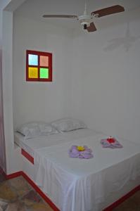 a bedroom with a white bed with a window at Pousada Gipsy in Arembepe