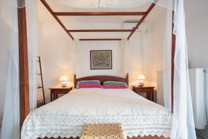 a bedroom with a large white bed with two lamps at Helen villa Paros in Ekatondapilianí