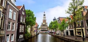 a canal in a city with a clock tower in the distance at Logeren op Dijk43 in Broek op Langedijk