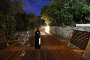 eine Flasche Wein auf einem Holztisch mit Weingläsern in der Unterkunft Makarska city center1 willa in Makarska