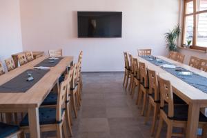 a room with long tables and chairs and a flat screen tv at Weingut und Gästehaus Wetzler in Vendersheim