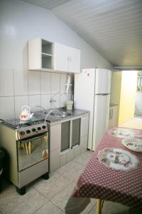 una pequeña cocina con fogones y nevera. en KIT 5 - Estúdio com churrasqueira piscina ar wifI vaga cozinha, en Itapema