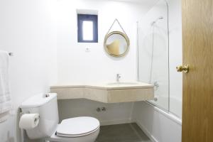 a bathroom with a toilet, sink, and mirror at Baixa Hotel in Bragança