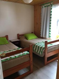 a bedroom with two beds with green sheets and a window at Cabañas El Sol de Dichato in Dichato