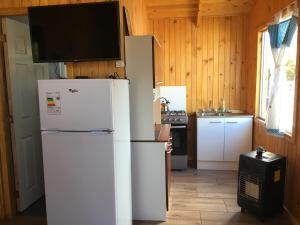 a kitchen with two white refrigerators and a tv at Cabañas El Sol de Dichato in Dichato