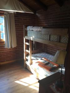 1 dormitorio con 2 literas y pared de ladrillo en Cabaña Aires del Bosque en Balneario Mar Azul