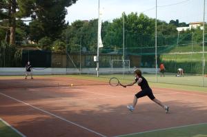 two people playing tennis on a tennis court at Green Garden Village in Sirolo