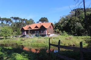 una casa roja con una valla al lado de un estanque en Pousada dos Cataventos, en São Francisco de Paula