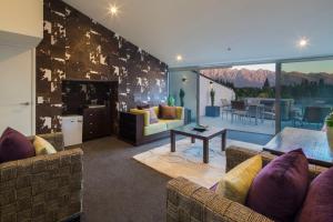a living room with couches and a living room with a fireplace at Shotover Penthouse & Spa by Staysouth in Queenstown