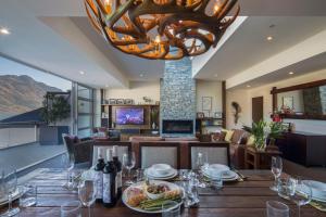 una sala da pranzo con tavolo e lampadario pendente di Shotover Penthouse & Spa by Staysouth a Queenstown