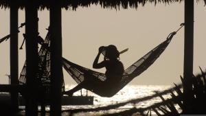 a woman sitting in a hammock on the beach at Hotel Punta Faro in Isla Mucura