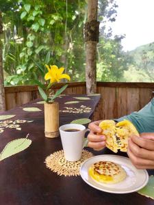 Huigra的住宿－Cabañas Samay Mágico Ecolodge，坐在餐桌上的人,带上一盘早餐食品