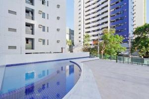 a swimming pool in front of two tall buildings at Flat 1402 com vista para mar, Edf Home Club Porto do Mar in Recife