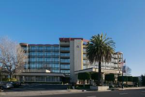 a tall building with a palm tree in front of it at Oakland Airport Executive Hotel in Oakland